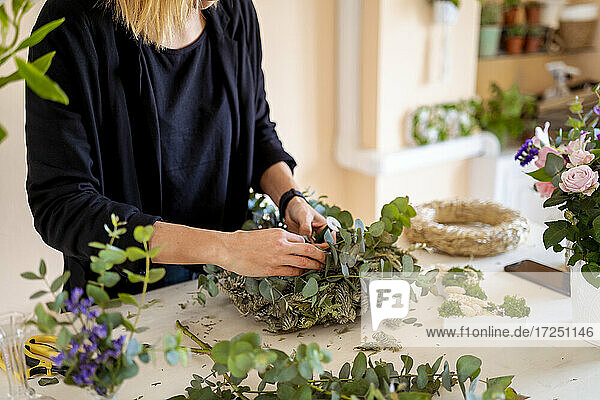 Eine Floristin fertigt in einem Workshop ein Blumenarrangement aus Blättern an