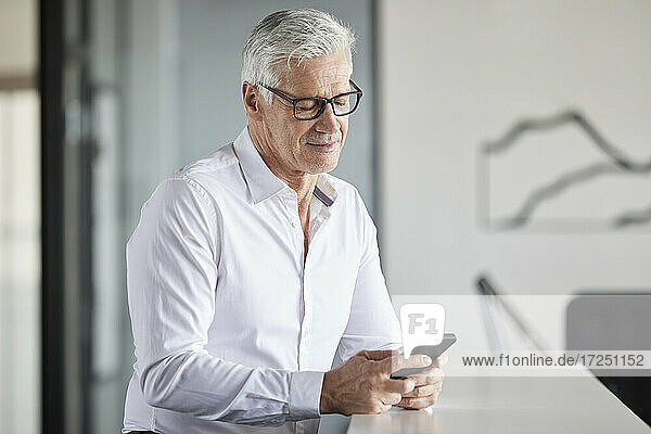 Smiling entrepreneur using mobile phone at office
