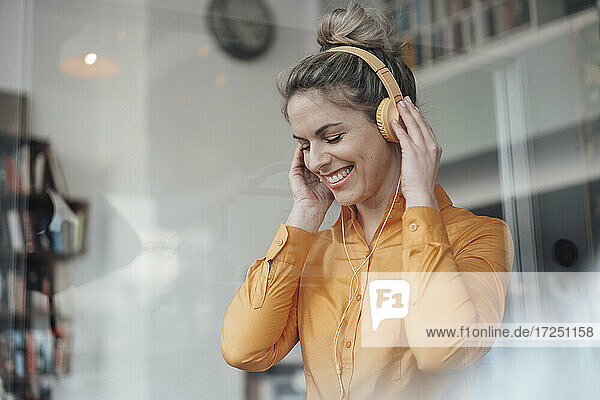 Glückliche Besitzerin hört Musik über Kopfhörer in einem Café