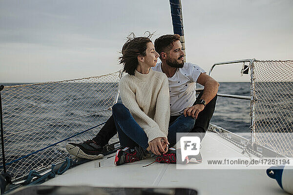 Girlfriend and boyfriend sitting on sailboat during vacation