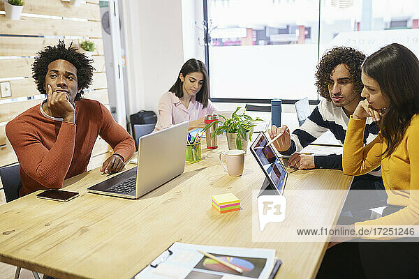 Geschäftsleute diskutieren über ein digitales Tablet am Konferenztisch im Büro