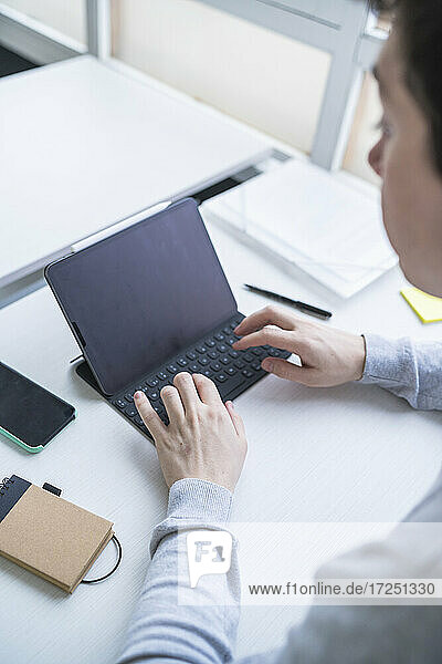 Männlicher Unternehmer mit digitalem Tablet am Schreibtisch im Büro