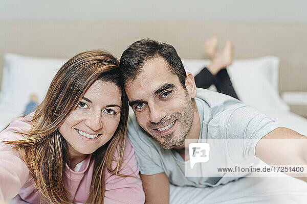 Smiling couple lying together on bed in hotel room
