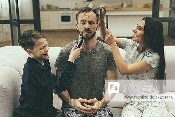 Family giving haircut to man at home