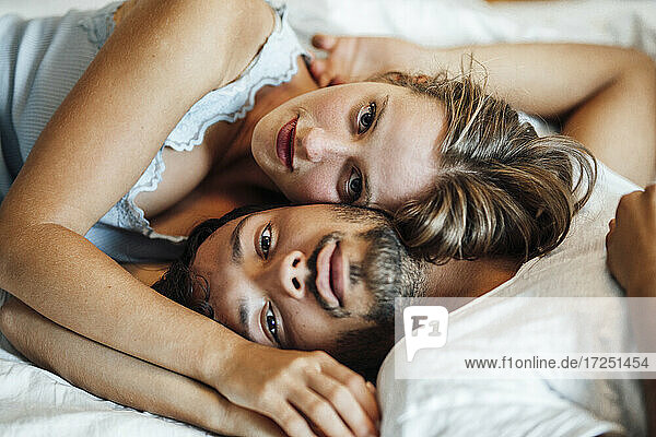 Romantic young couple lying on bed at home