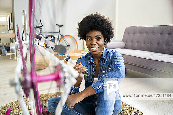 Glückliche junge Frau repariert Fahrrad zu Hause