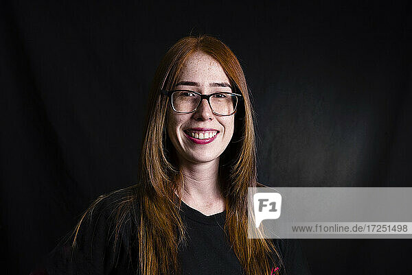 Smiling woman wearing eyeglasses against black background