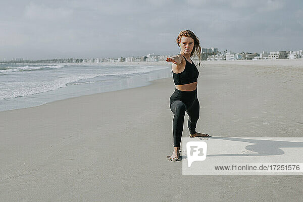 Schöne Frau übt Yoga am Strand an einem sonnigen Tag