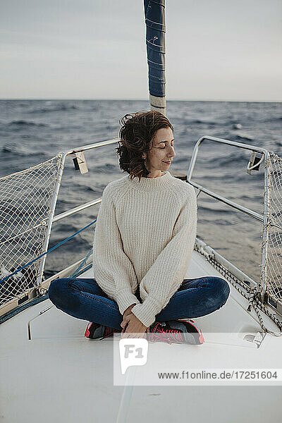 Frau mit geschlossenen Augen auf einem Boot im Meer sitzend im Urlaub