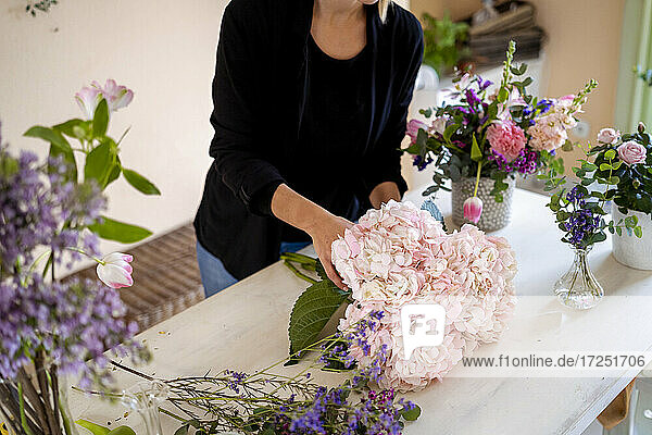 Frau macht Blumenarrangement auf einem Tisch in einer Werkstatt