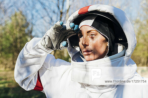 Weibliche Astronautin grüßt  während sie an einem sonnigen Tag wegschaut