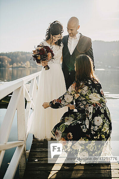 Brautjungfer hilft Hochzeitspaar auf Steg über See