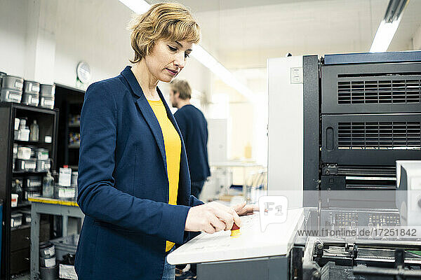 Ingenieurin an der Druckmaschine bei der Arbeit mit einem Kollegen in der Industrie