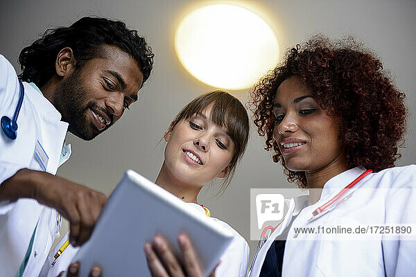 Männliche und weibliche Fachkräfte des Gesundheitswesens diskutieren über ein digitales Tablet