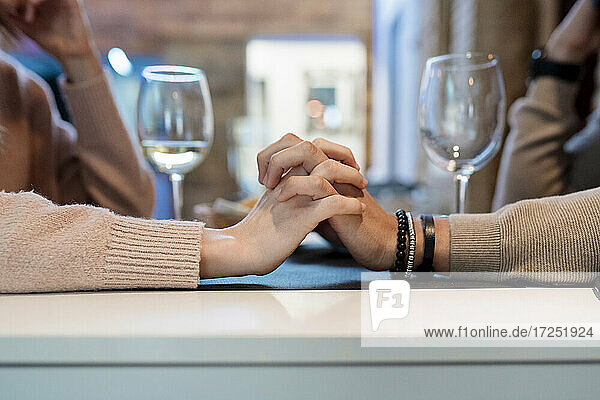 Couple with hands clasped sitting at restaurant