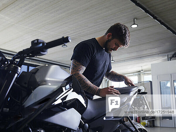 Repairman installing motorcycle seat at workshop