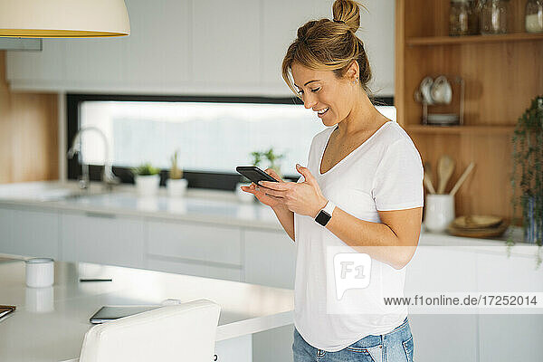 Geschäftsfrau benutzt Smartphone in der Küche zu Hause