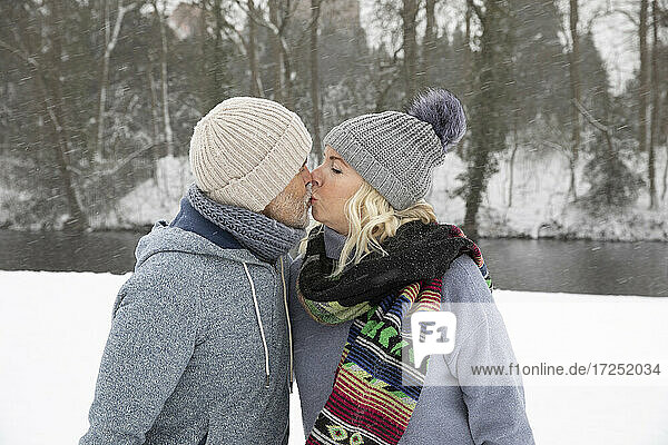 Senior couple kissing while standing at park during winter