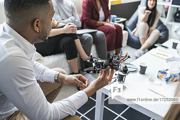 Afrikanischer männlicher Ingenieur  der mit Kollegen während einer Besprechung in einem Coworking-Büro über eine Drohne diskutiert
