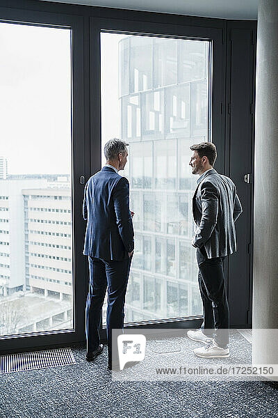 Business people discussing while standing by window in office