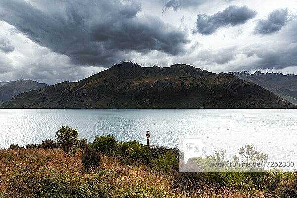 Neuseeland  Otago  Queenstown  Rückansicht eines Mannes mit Blick auf einen See unter Gewitterwolken
