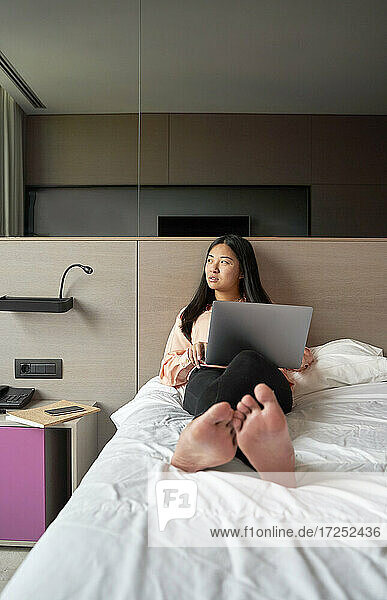 Nachdenkliche Unternehmerin mit Laptop im Hotel sitzend