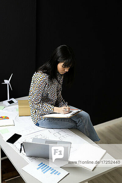 Unternehmerin beim Schreiben auf dem Schreibtisch im Büro sitzend