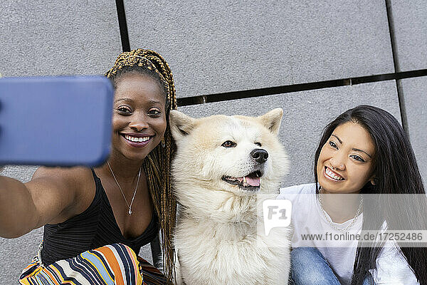 Multi-ethnische Freundinnen machen Selfie mit Hund im Freien