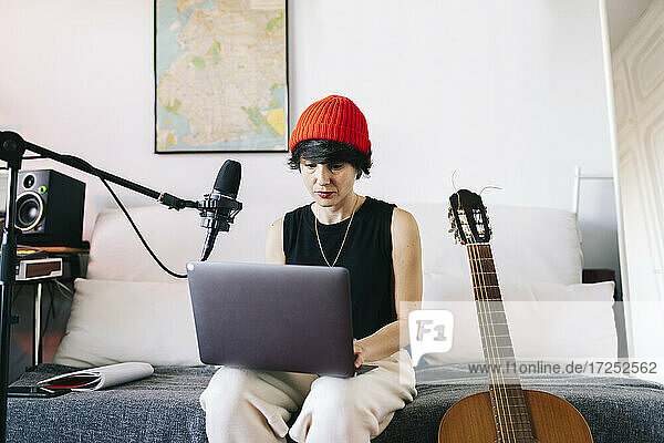 Female music composer using laptop in recording studio
