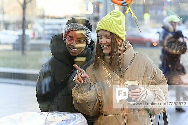 Female friends in knit hat enjoying window shopping during winter