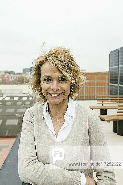 Smiling female entrepreneur standing on office terrace