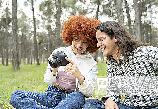 Lächelnde Frau zeigt Kamera an männlichen Freund während Party im Wald