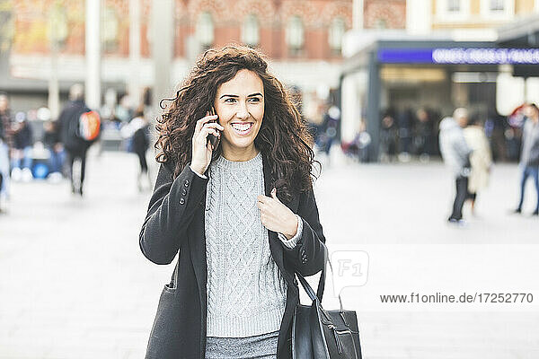 Glückliche Geschäftsfrau mit Mobiltelefon in einer Straße in der Stadt