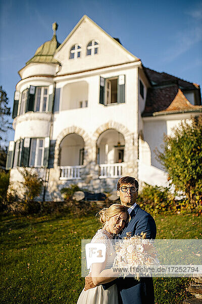 Neuvermähltes Paar umarmt sich vor einer Villa