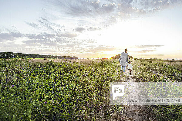 Mutter zu Fuß mit Baby Sohn entlang Landschaft Feldweg bei Sonnenuntergang