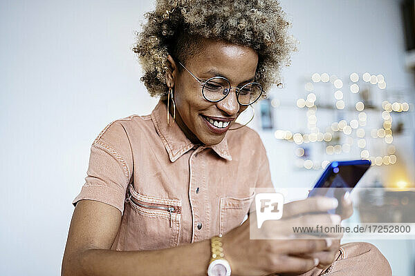 Female entrepreneur with eyeglasses using smart phone at home office