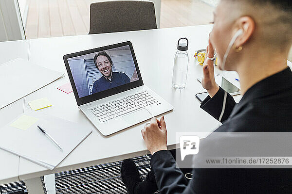 Unternehmerin winkt mit der Hand zum Videoanruf auf dem Laptop im Büro