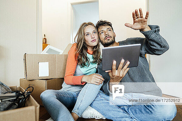 Junges Paar sitzt mit digitalem Tablet und plant zu Hause
