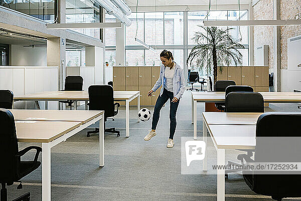 Geschäftsfrau spielt mit Fußball im Coworking-Büro