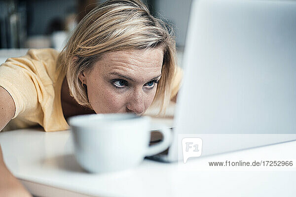 Müde blonde Geschäftsfrau mit Blick auf den Laptop