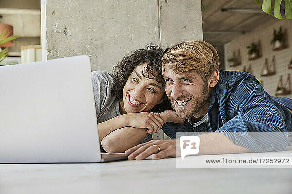 Glückliches Paar  das gemeinsam den Laptop in seiner Wohnung betrachtet