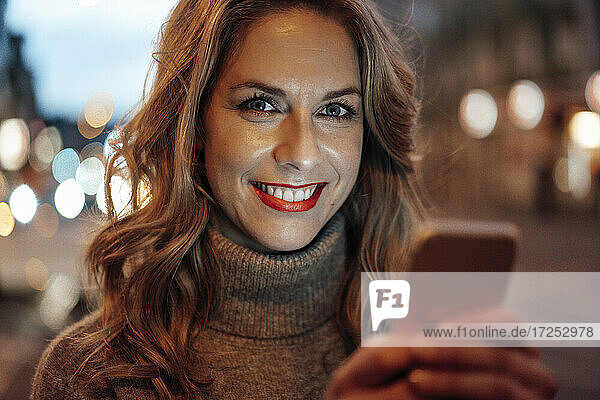 Lächelnde blonde Frau hält Smartphone