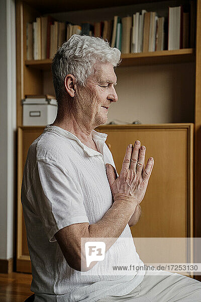 Man with hands clasped meditating at home