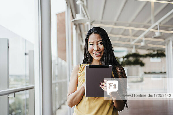Smiling businesswoman holding digital tablet at office