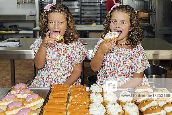 Zwillingsschwestern essen Gebäck in einer Bäckerei