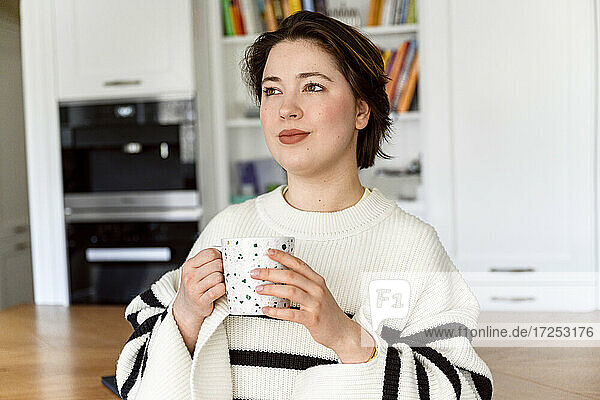 Beautiful woman holding coffee cup while looking away