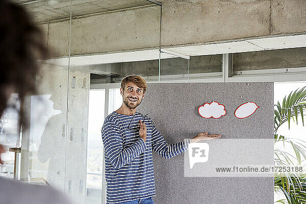 Lächelnder Mann gestikuliert  während er vor einer Trennwand in seiner Wohnung steht