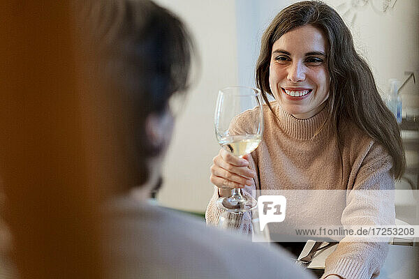 Smiling woman with wine glass looking at boyfriend in restaurant