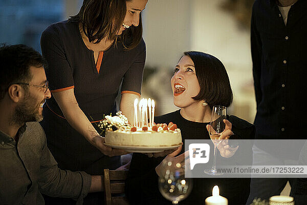 Überrascht Frau Blick auf weiblichen Freund hält Geburtstagskuchen zu Hause