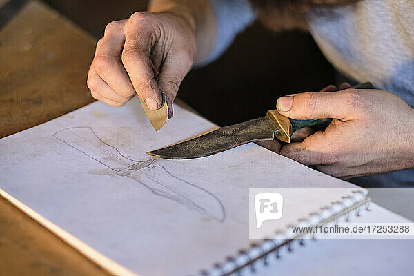 Handwerker hält Messer auf Skizzenblock in der Werkstatt